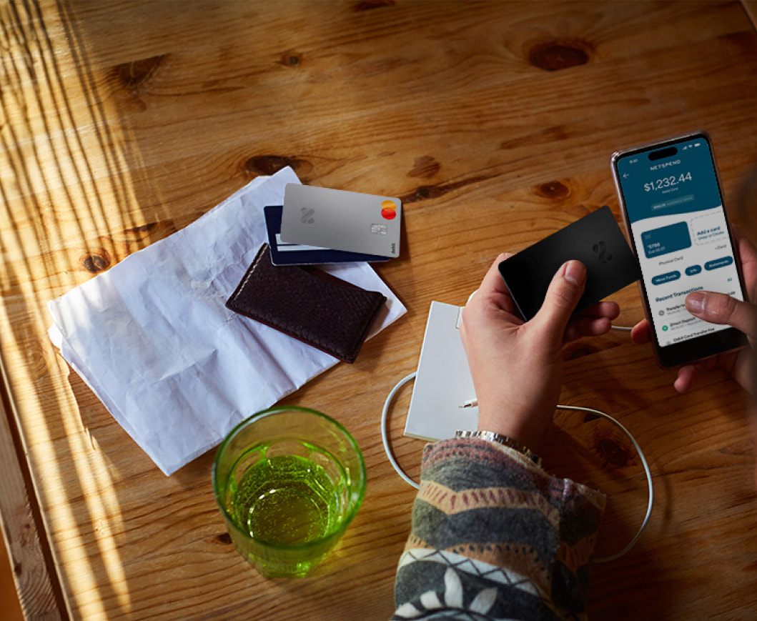 Someone holding a Netspend Card while viewing the Netspend app dashboard