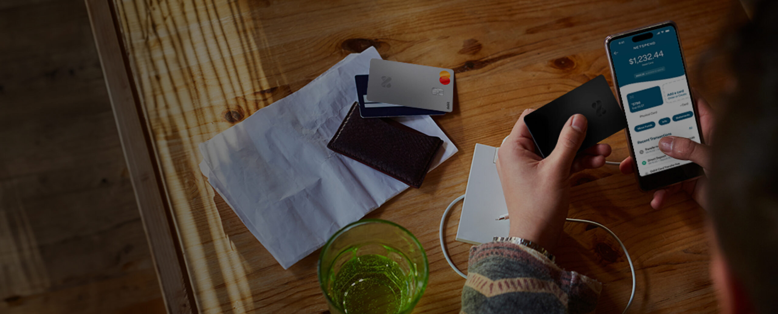 Someone holding a Netspend Card while viewing the Netspend app dashboard